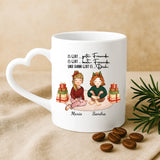 Weiße personalisierte Weihnachtstasse mit Herzhenkel mit Freundinnen-Illustration für Glühwein zur Weihnachtsfeier als Geschenk von Love & Faith